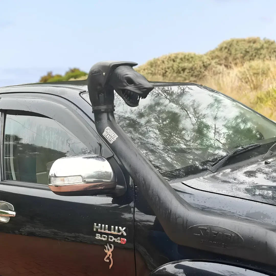 Black Toyota Hilux with a mounted Snorkel Beast on the snorkel head against a natural background.