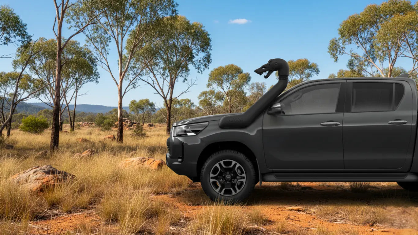 Black pickup truck in a natural landscape with trees and open sky, with a snorkel beast of a shark on its snorkel head